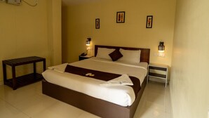 A hotel room with a large bed, bedside tables, wall-mounted lamps, and a ceiling fan. - Hotel The King's (Port Blair)
