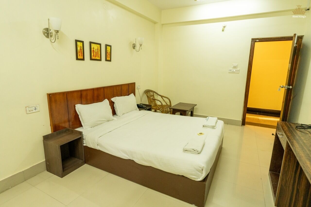 Una habitación de hotel con una cama de madera, una mesita de noche pequeña, una silla y un escritorio.