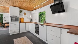 Une cuisine moderne avec des meubles blancs, un plan de travail en bois et un lave-vaisselle encastré.
