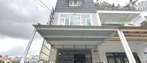 Un edificio con techo de tejas, un cartel y una entrada protegida por una reja.