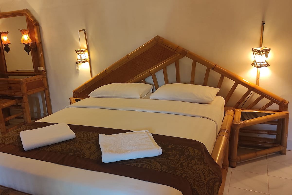 A neatly made bed with white linens, a wooden headboard, and two bedside lamps.