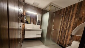 A modern bathroom with a large mirror, a white sink, and a shower enclosure.