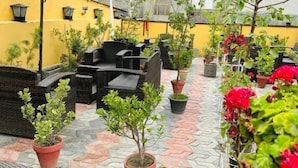 A rooftop patio with outdoor furniture, potted plants, and a view of mountains.