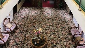 A grand lobby with a large chandelier, ornate ceiling, and a patterned carpet.