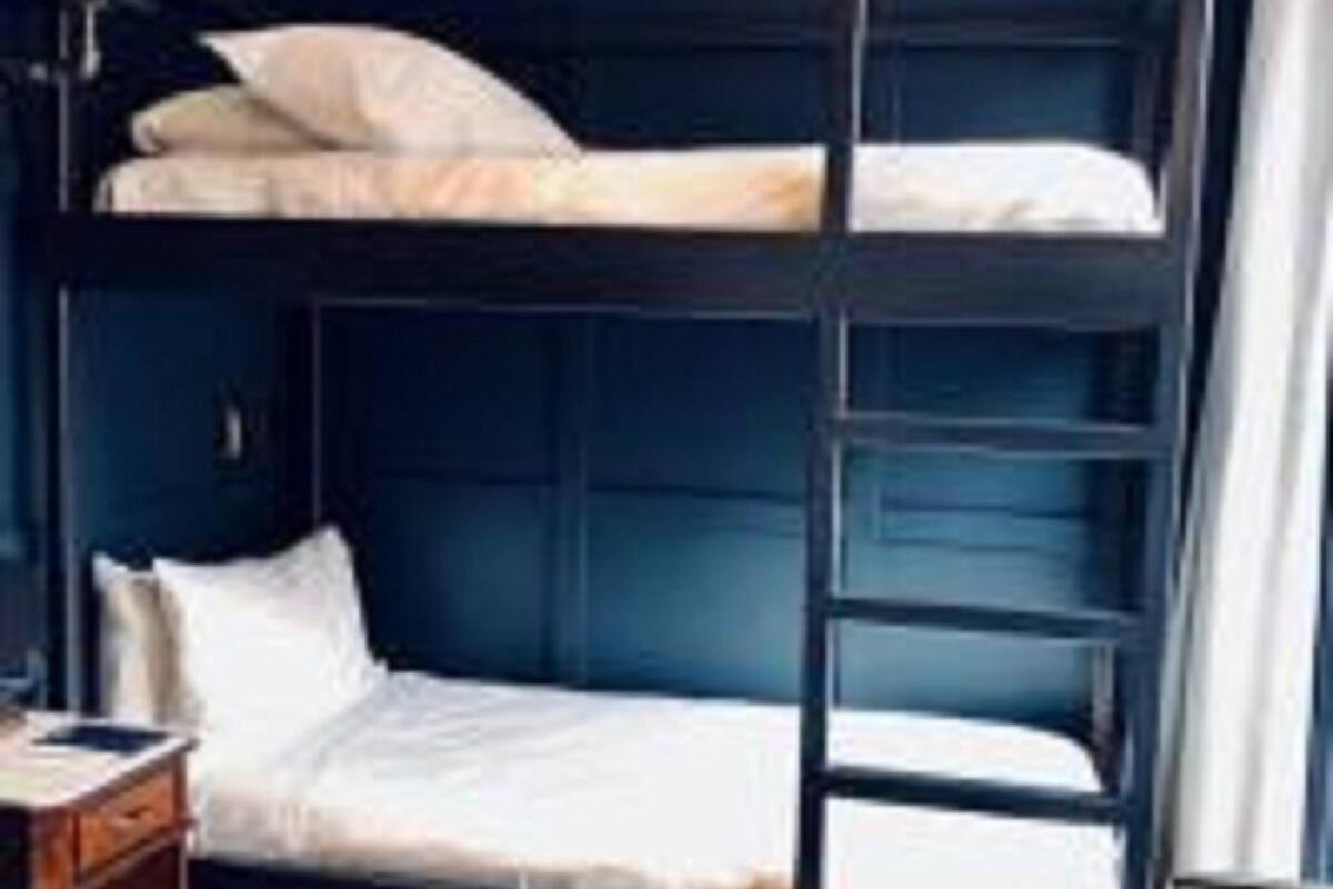 A bunk bed with a wooden ladder, a bedside table, and a nightstand.