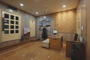 A reception area with a desk, a computer, a Christmas tree, and framed pictures on the wall. - Hinduja Haveli  (Jodhpur)