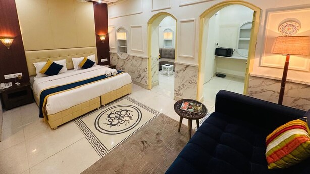 A hotel room with a large bed, a sofa, a small table, and a bathroom visible through an archway. - Hinduja Haveli  (Jodhpur)