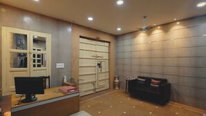 A reception area with a desk, computer, seating, and a wall with a large cabinet. - Hinduja Haveli  (Jodhpur)