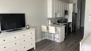 A modern kitchen with white cabinets, a built-in oven, and a stainless steel refrigerator.