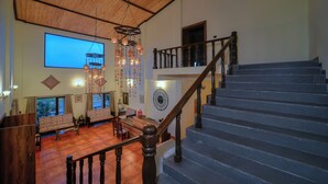 Un amplio salón con techo de madera, una escalera y un ventanal grande.