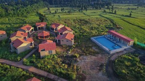 Vista aérea de un resort con varias construcciones, una piscina y campos verdes circundantes.