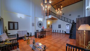 Amplia zona de estar con techo alto, una escalera y un mostrador de recepción.