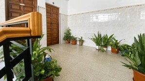 A hallway with a wooden staircase, tiled walls, and multiple potted plants. - Comeback Torrenueva Costa (Torrenueva Costa)