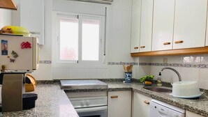 A kitchen with a granite countertop, white cabinets, a built-in oven, a dishwasher, and a window with a view. - Comeback Torrenueva Costa (Torrenueva Costa)