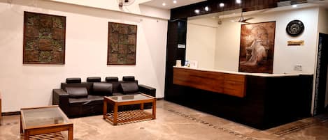 A reception area with a reception desk, a black leather sofa, a glass coffee table, and artwork on the walls.