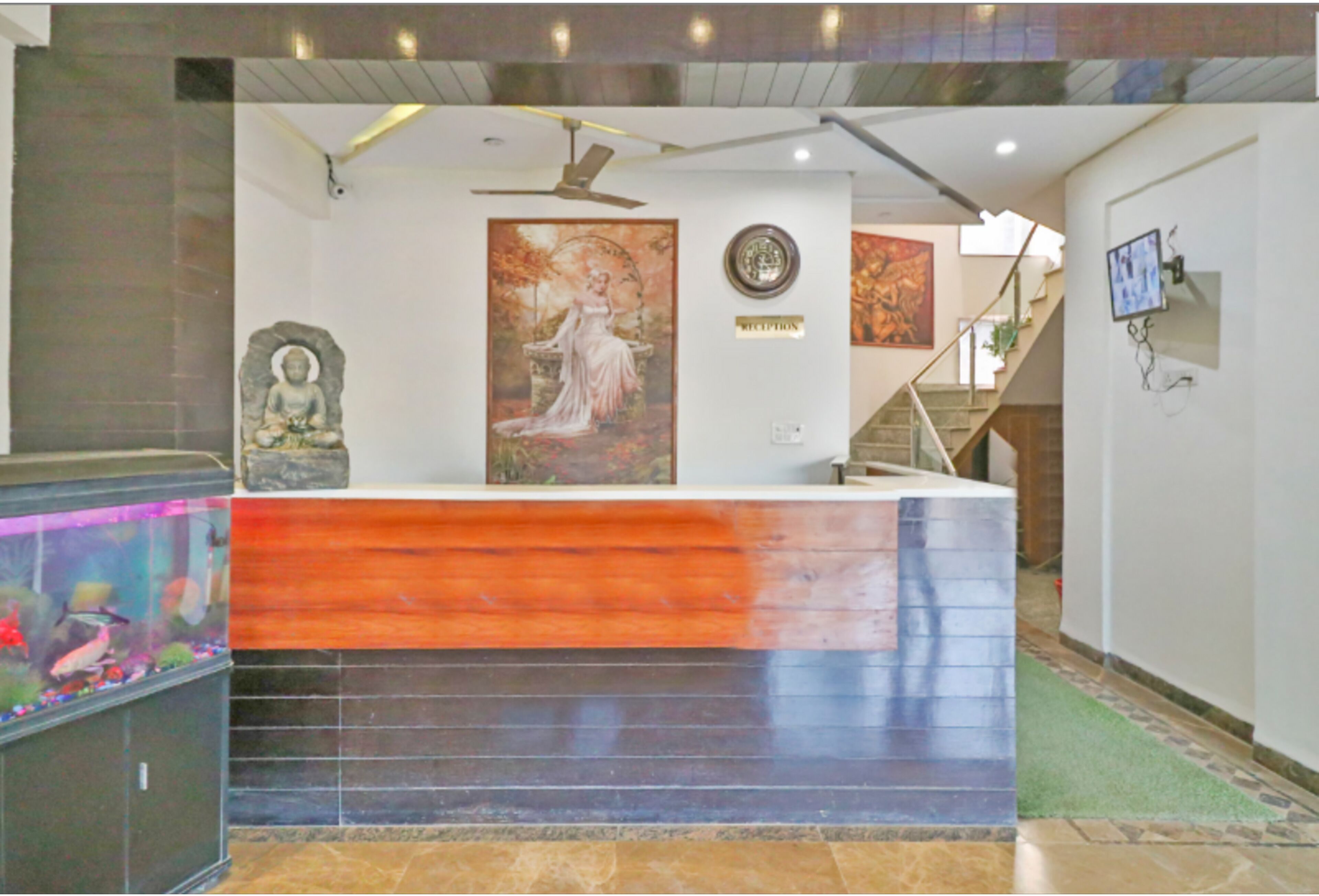 A reception area with a wooden reception desk, a Buddha statue, and a framed painting on the wall.