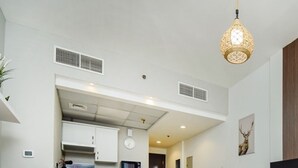A modern hotel room with a sofa bed, a flat-screen TV, a dining table, and a kitchen area visible through an open door. - Stylish Studio in Dubai Marina Close to the Beach, Mall and Metro (Dubai)