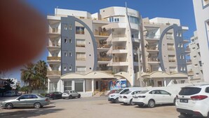 A multi-story building with a modern architectural design, featuring balconies and a central entrance.