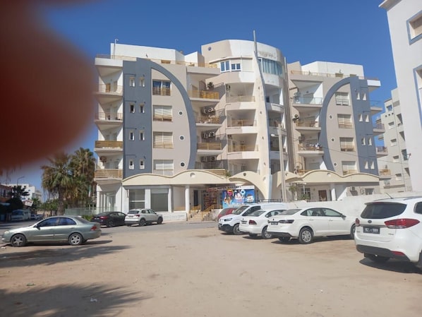 A multi-story building with a modern architectural design, featuring balconies and a central entrance.