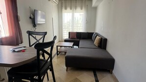 A living room with a sofa, a coffee table, and a TV mounted on the wall.