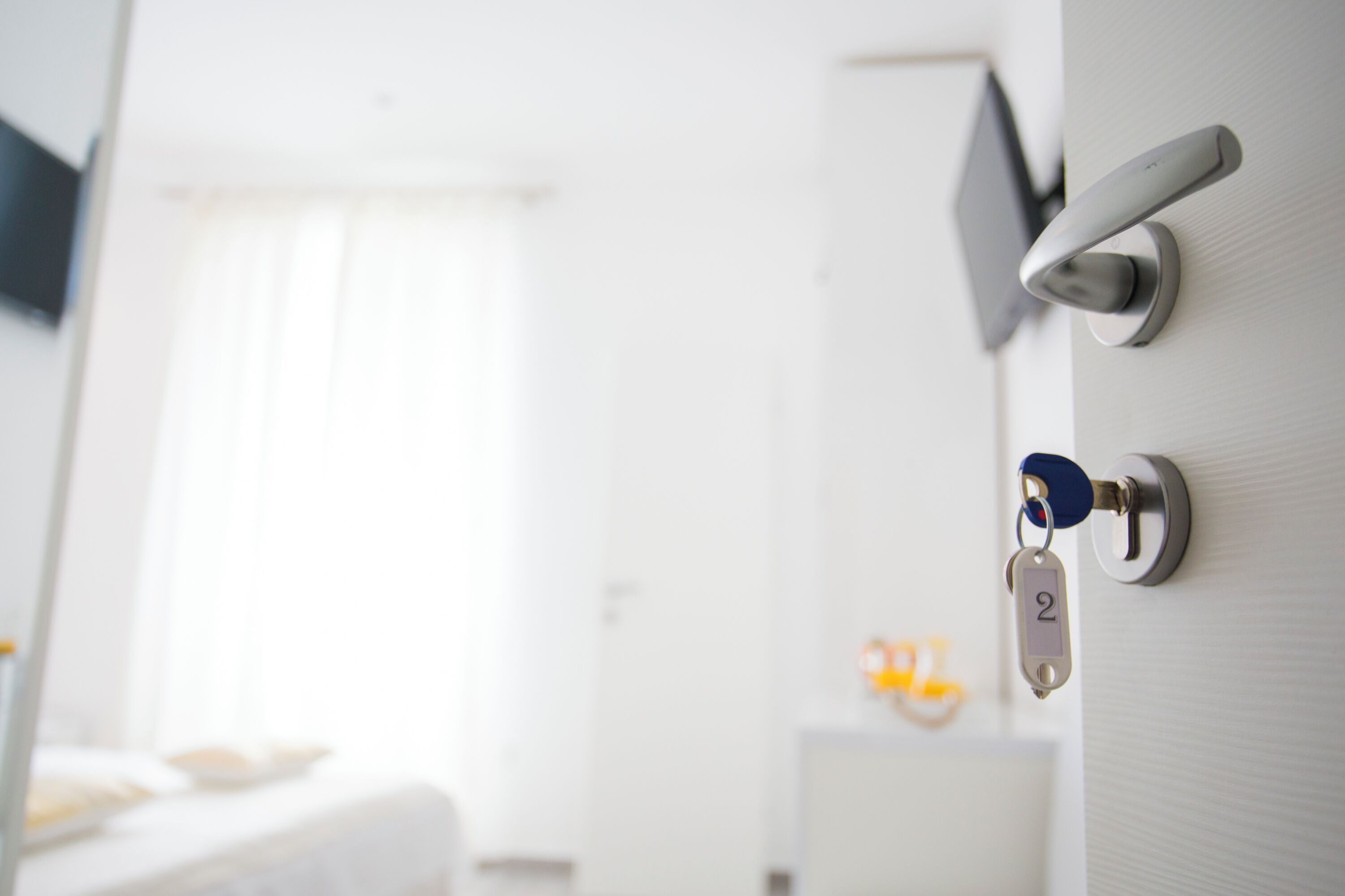 Une porte de chambre d’hôtel équipée d’un système de verrouillage à carte magnétique et d’un porte-clés portant le numéro 2.