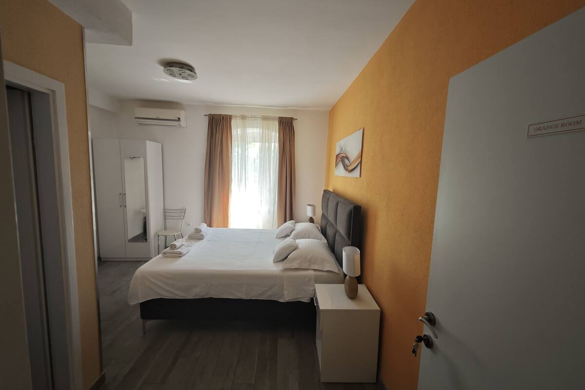 A hotel room with a bed, bedside table, and a door.