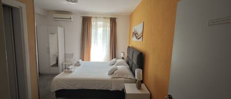 Una habitación de hotel con cama, mesita de noche y puerta.