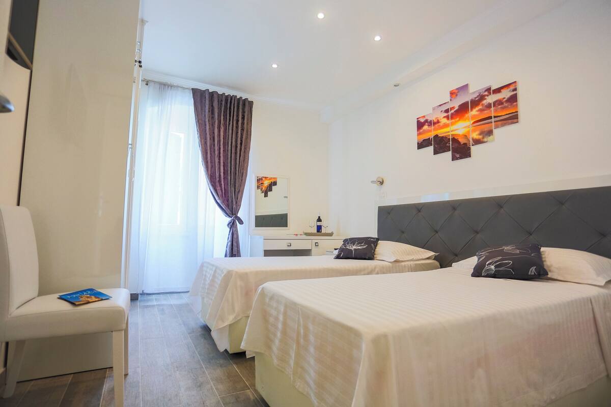 A hotel room with two beds, a desk, and a chair.