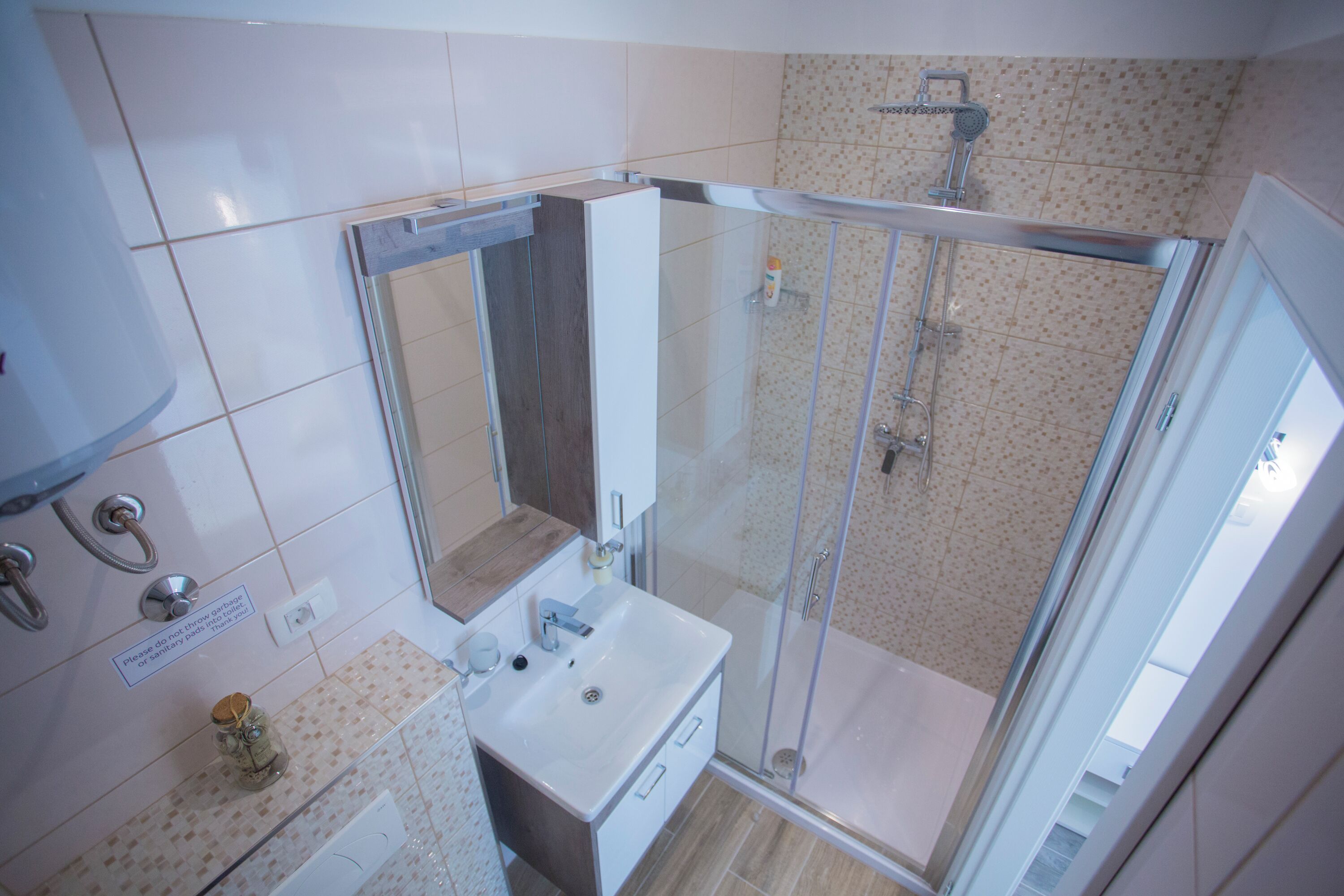A modern bathroom with a glass-enclosed shower, a white sink, and a mirror.