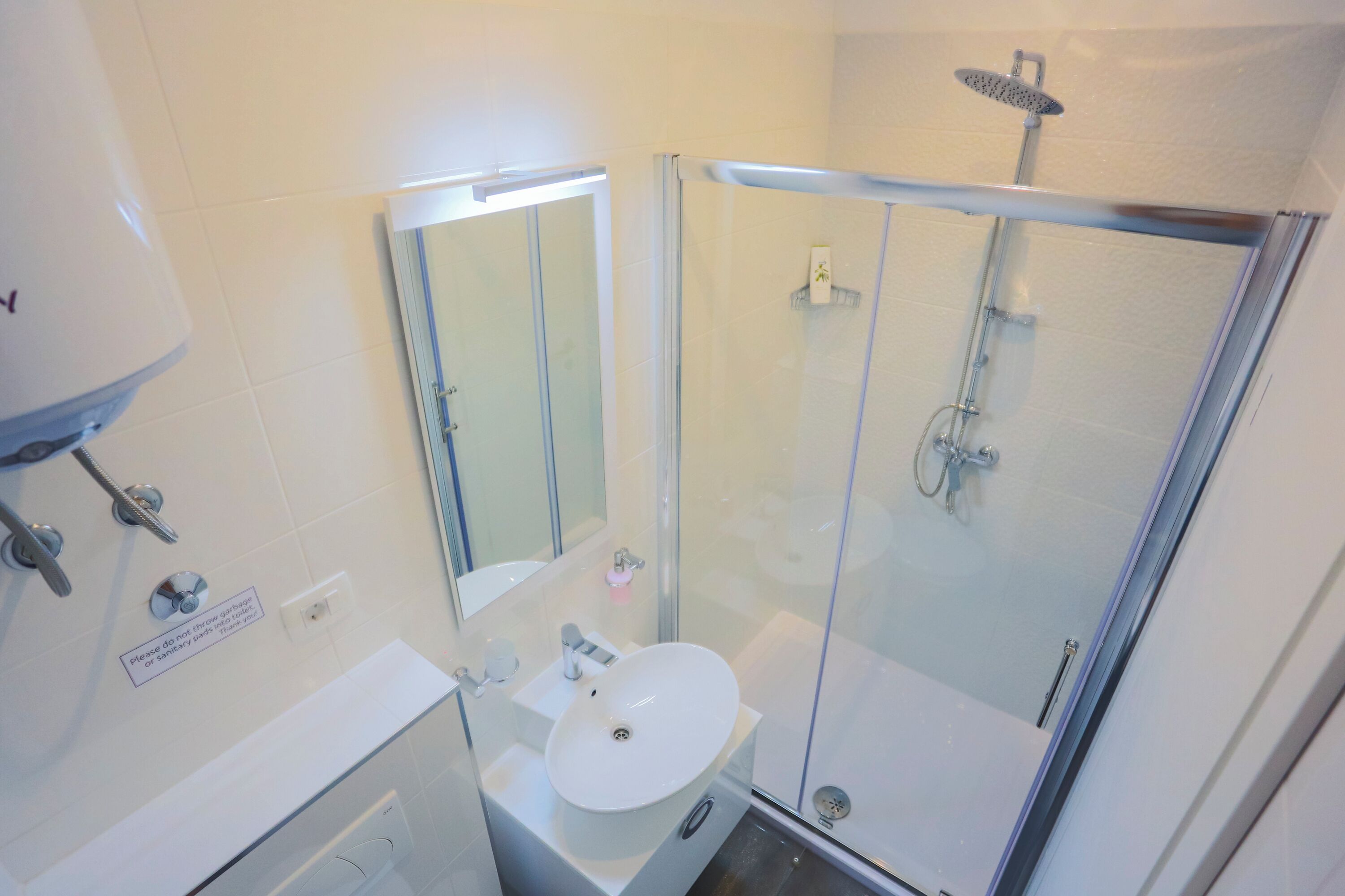 A bathroom with a glass-enclosed shower, a sink, and a mirror.