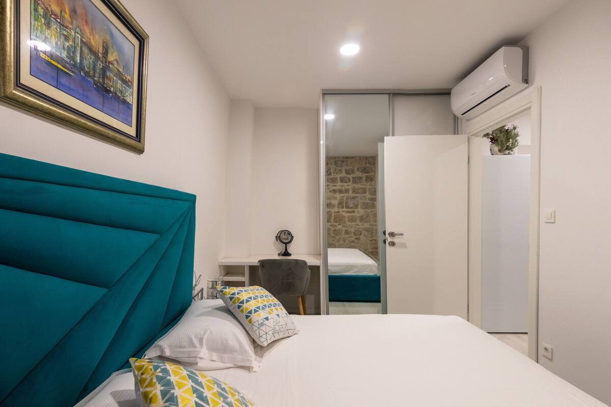 A bedroom with a large bed, a bedside table, a mirror, and a wardrobe.