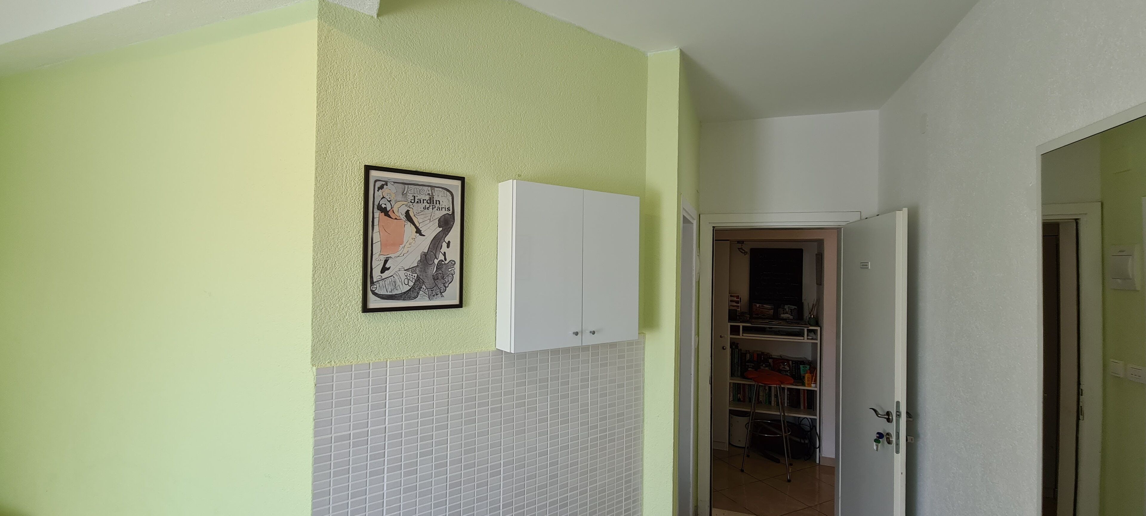 Eine Küche mit gefliestem Spritzschutz, einem weißen Schrank und einem gerahmten Bild an der Wand.