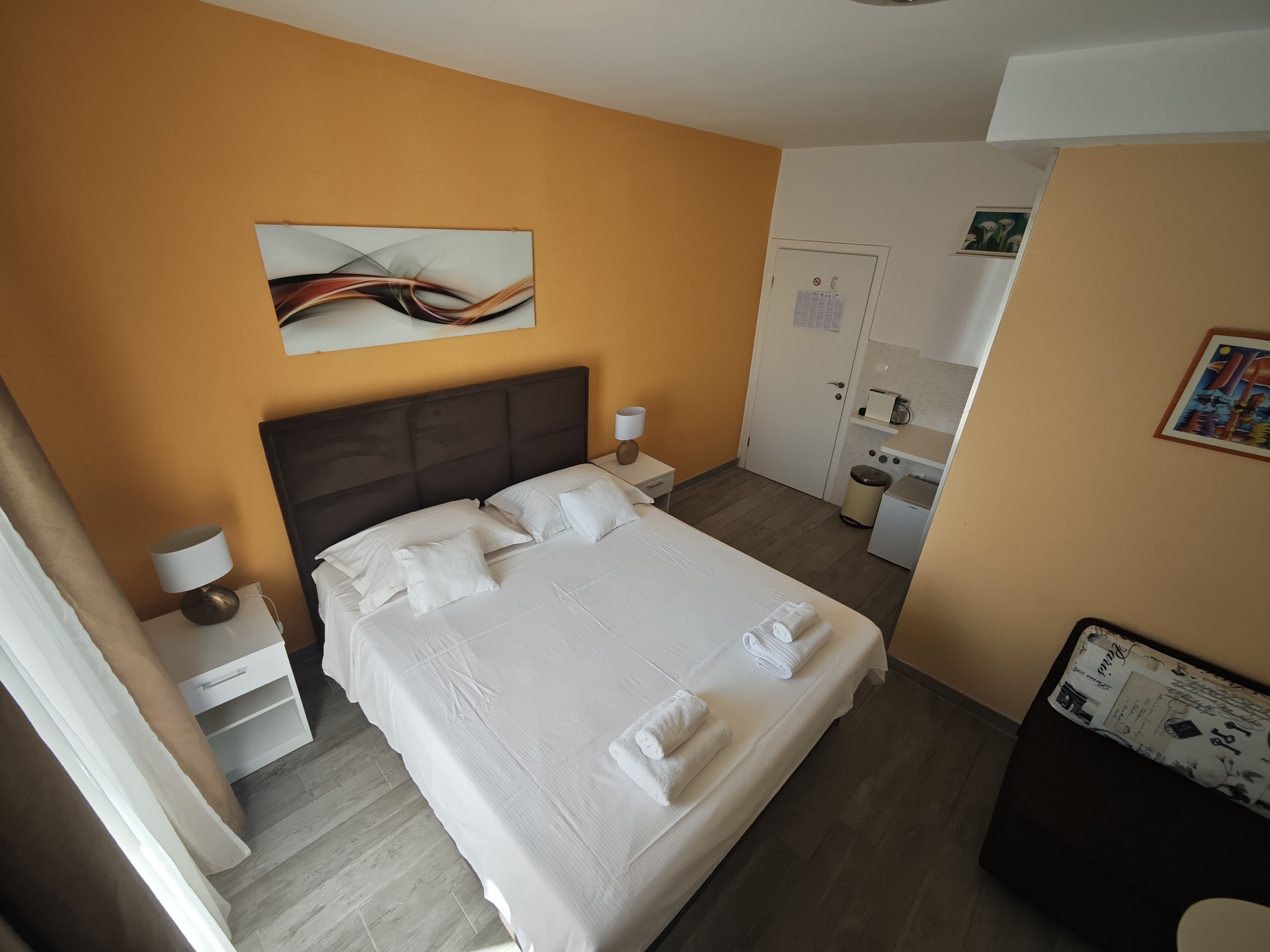 Hotelkamer met een bed, nachtkastje, bureau, kleine kitchenette en badkamer.