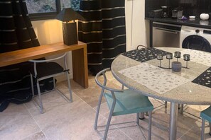 A dining area with a round table, chairs, a bench, and a kitchen in the background.