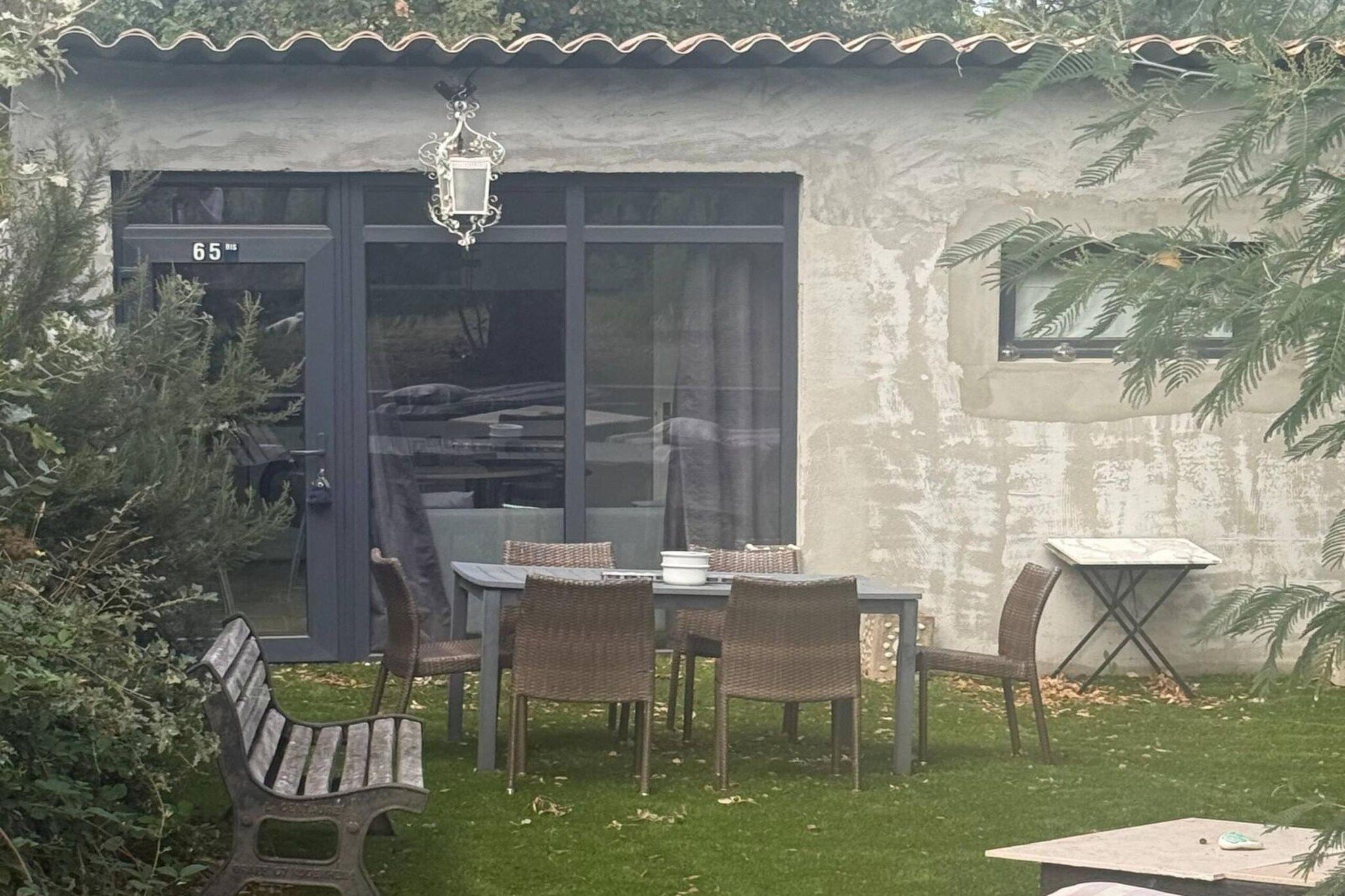 A patio area with a table and chairs, a bench, and a small table with a plant.