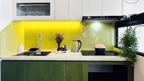A modern kitchen with a yellow backsplash, green cabinets, and a window with a view.