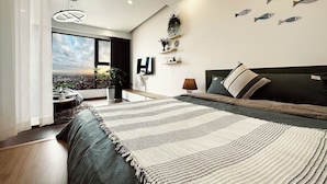 A modern bedroom with a large bed, a view of the city, and decorative fish wall art.