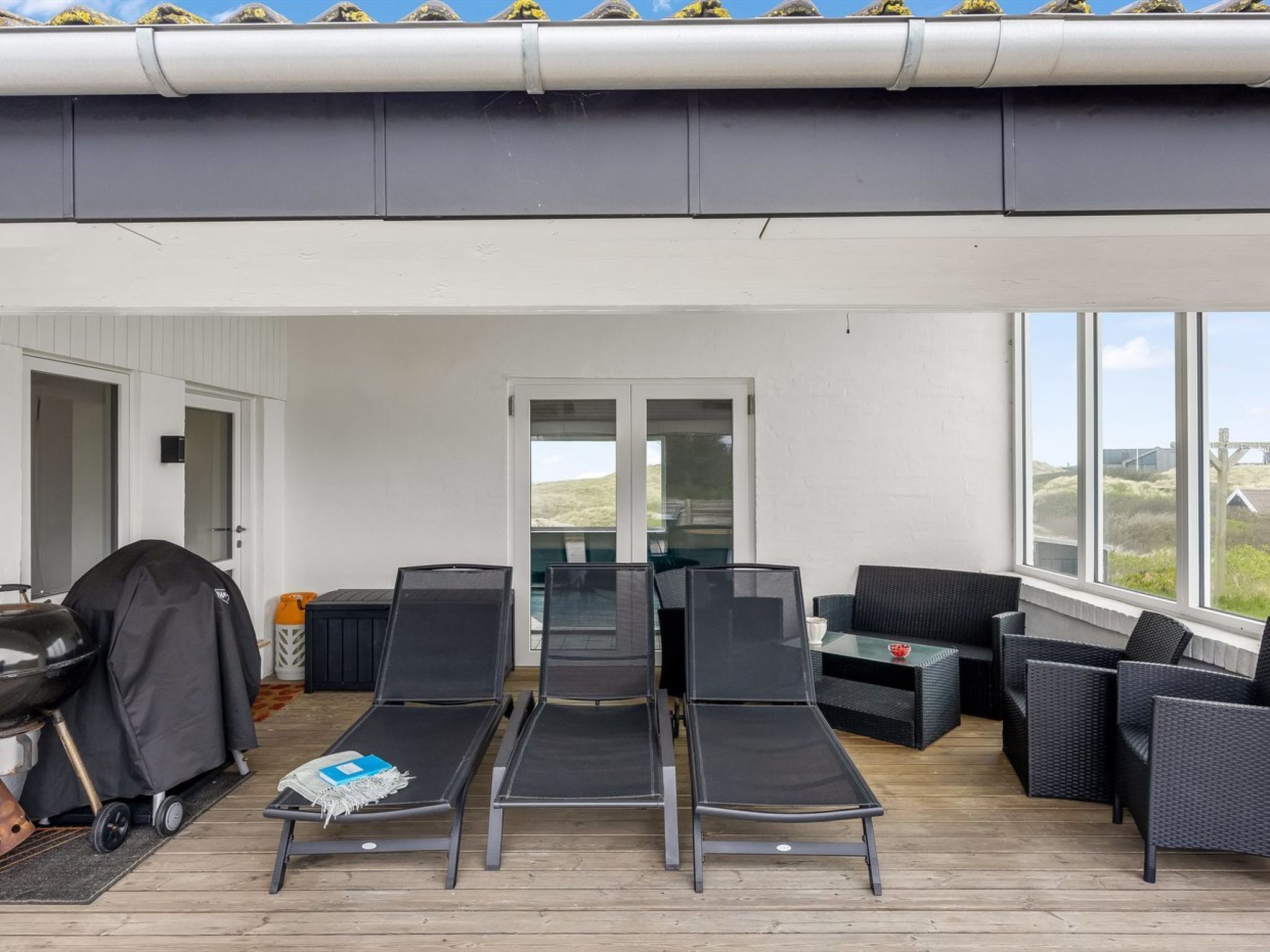 Un espace extérieur abrité, aménagé avec des fauteuils confortables et un barbecue.