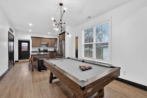 Una cocina moderna con armarios de madera, electrodomésticos de acero inoxidable y una mesa de billar con bolas.