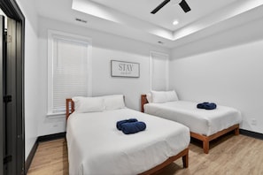 Una habitación con dos camas, un ventilador de techo y un cartel enmarcado en la pared.