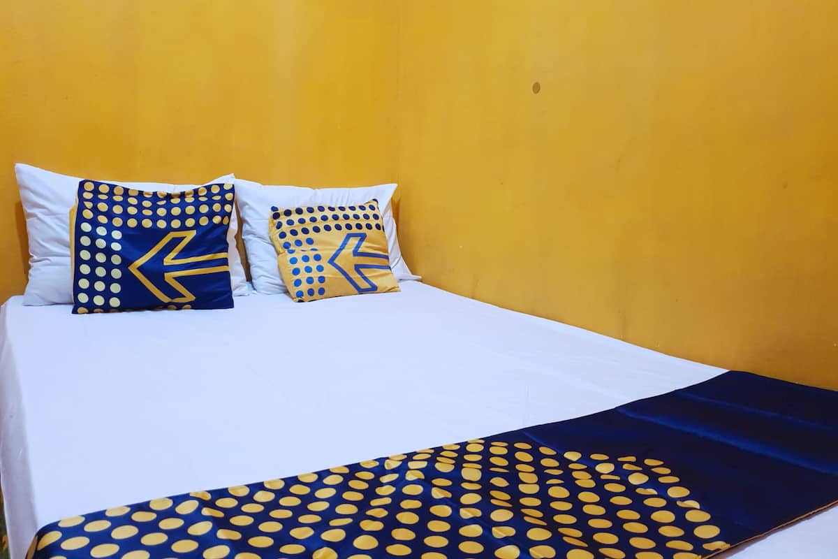 Una cama con sábanas blancas y dos almohadas decorativas con motivos azules y amarillos.
