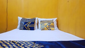 Un lit avec une literie blanche et deux coussins décoratifs aux motifs géométriques.