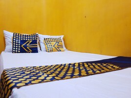 Una cama con sábanas blancas y dos almohadones decorativos con diseños geométricos.