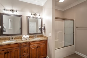 Une salle de bain avec deux lavabos, un grand miroir et une douche Ă parois de verre.