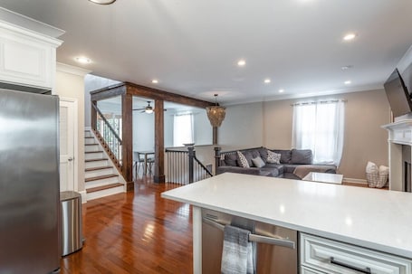 A modern kitchen with a central island, wooden flooring, and a staircase leading to another level.. Downtown Chatt | Sleeps 17 | Game Room +Huge Deck