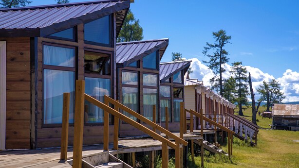 Eine Reihe von Holzhütten mit großen Fenstern und einer Holzterrasse.
