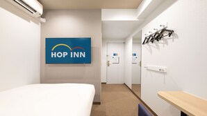 A hotel room with a bed, a desk, a chair, a wall-mounted air conditioner, and a sign with "HOP INN" logo. -  HOP INN Tokyo Iidabashi (Tokyo)
