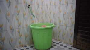 A green trash bin in a corner with a floral tile backsplash. - Hotel O Hunian 99 (Genteng)