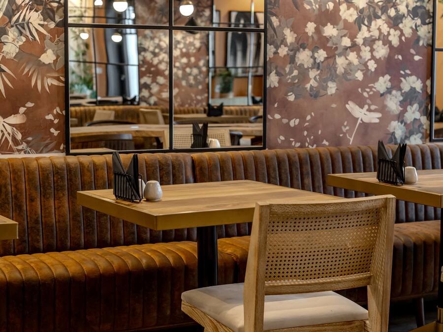 A restaurant interior with wooden booths, tables, and a large floral mural on the wall.