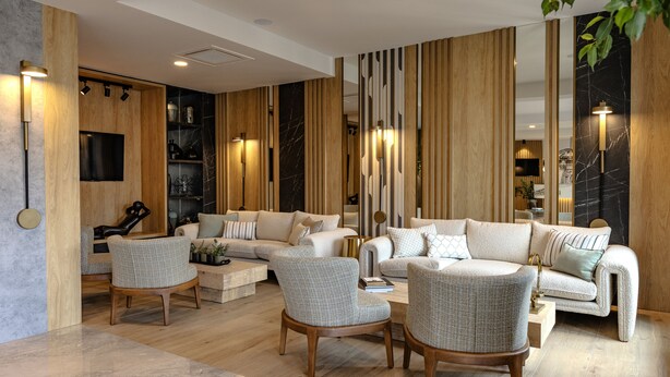 A modern living room with a sofa set, two armchairs, a coffee table, and a TV mounted on a wooden wall. - Hotel Branco Timisoara (Timisoara)